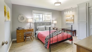 Un dormitorio con cama, cómoda, silla y ventana con persianas.