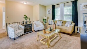 A living room with a beige sofa, two patterned armchairs, a glass coffee table, and a black side table. - Cozy Missouri Retreat w/ Deck & Grill, Near Hiking (Lee's Summit)