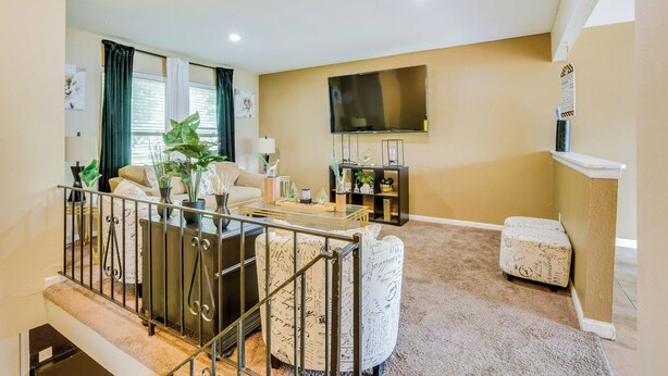 A living room with a sofa, coffee table, and a TV mounted on the wall. - Cozy Missouri Retreat w/ Deck & Grill, Near Hiking (Lee's Summit)