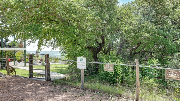 Un'area recintata con cartelli che indicano un'area parcheggio per ospiti e un avviso riguardante una zona riservata a cani non udenti.