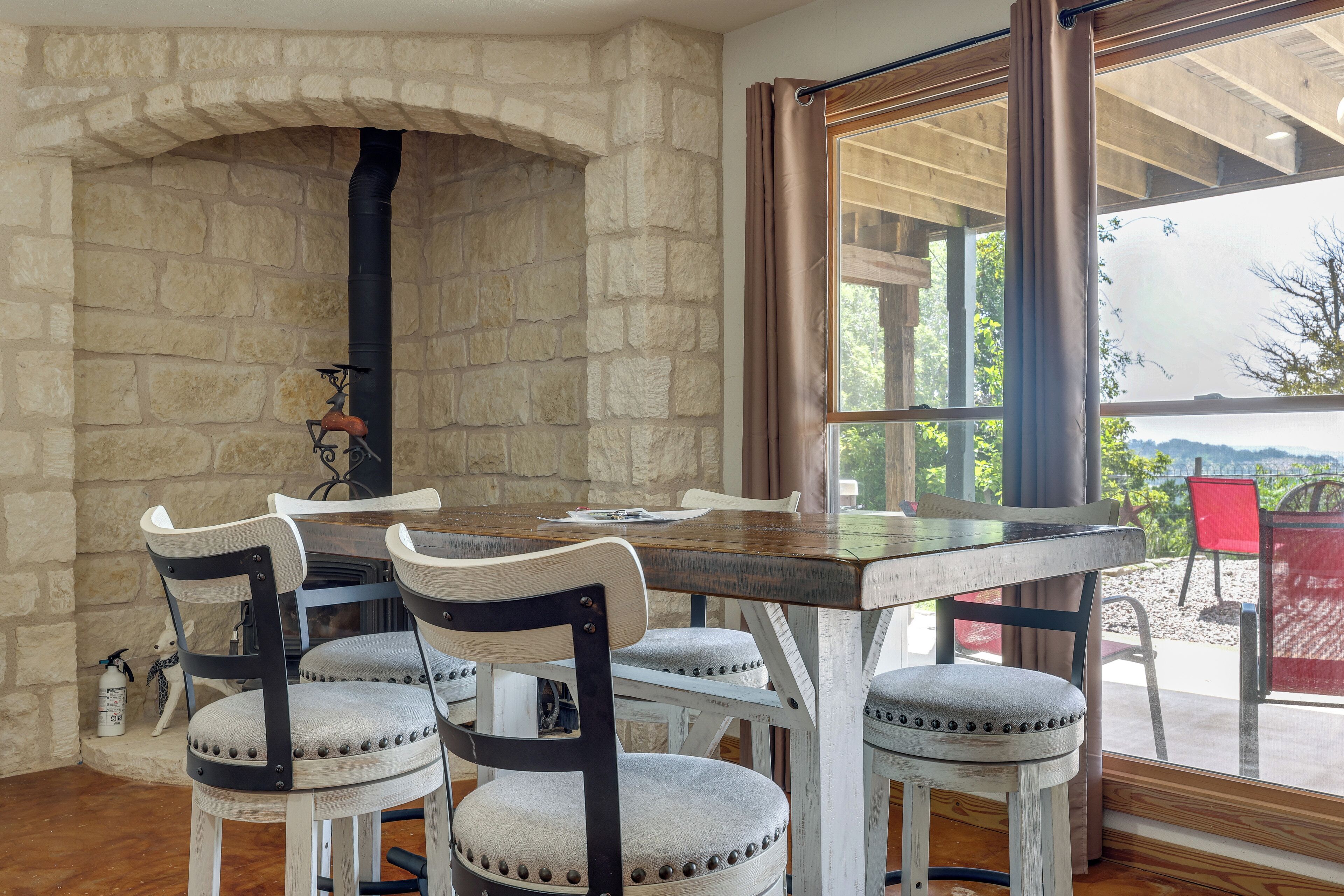 A dining area with a stone wall, a fireplace, and a view through a window.