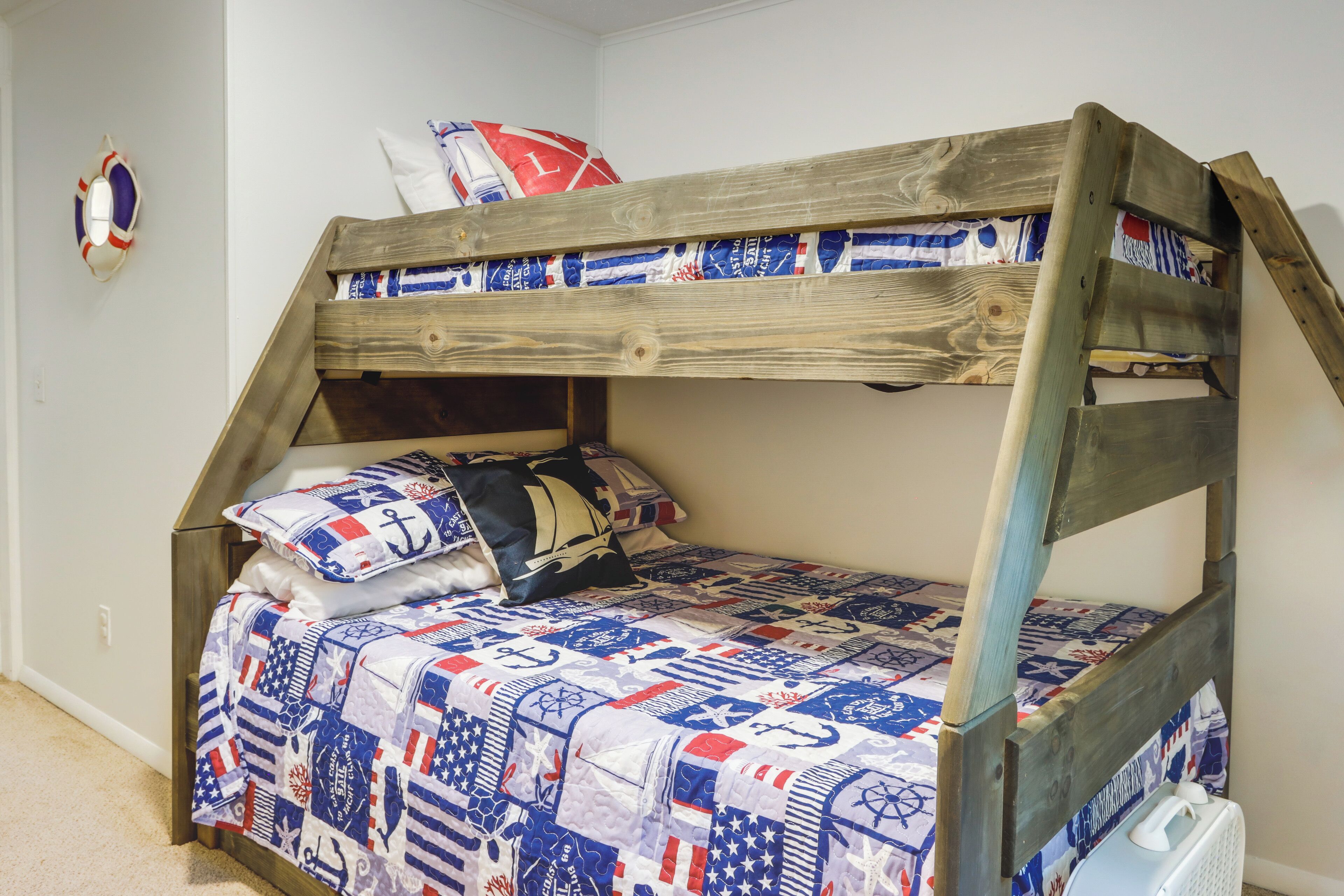 A bunk bed with a quilted bedspread featuring nautical and patriotic designs.