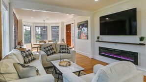 A modern living room with a large flat-screen TV, a fireplace, and comfortable seating. - 1 Mi to Falls View Park: Convenient Cohoes Retreat (Cohoes)