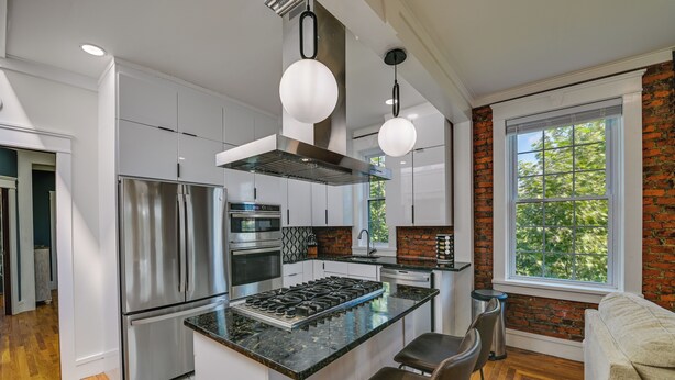 A modern kitchen with stainless steel appliances, a central island, and a large window with a view of trees. - 1 Mi to Falls View Park: Convenient Cohoes Retreat (Cohoes)