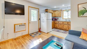 A compact living space with a TV, a refrigerator, wooden cabinets, and a sofa. - Secluded Ozark Mtn Cottage w/ Wraparound Deck (Eureka Springs)