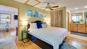 A bedroom with a bed, a ceiling fan, artwork on the wall, a desk with a chair, and a window. - Secluded Ozark Mtn Cottage w/ Wraparound Deck (Eureka Springs)