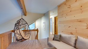 A cozy loft bedroom with a hanging chair, a sofa, and a wooden wall. - Pocono Lake Retreat w/ Fire Pit: Near Beach! (Pocono Lake)