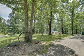 Un área boscosa con un sendero de grava que conduce a un edificio con mesas al aire libre.