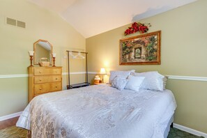 A bedroom with a large bed, a dresser, a mirror, a lamp, and a framed picture on the wall.