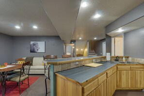 Una cocina moderna con una isla central, armarios de madera y una zona de comedor con alfombra roja.