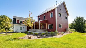 A two-story house with a red exterior, a covered porch, and a well-maintained lawn. - Acadia Home w/ Rooftop Deck - Close to Trails! (Mount Desert)