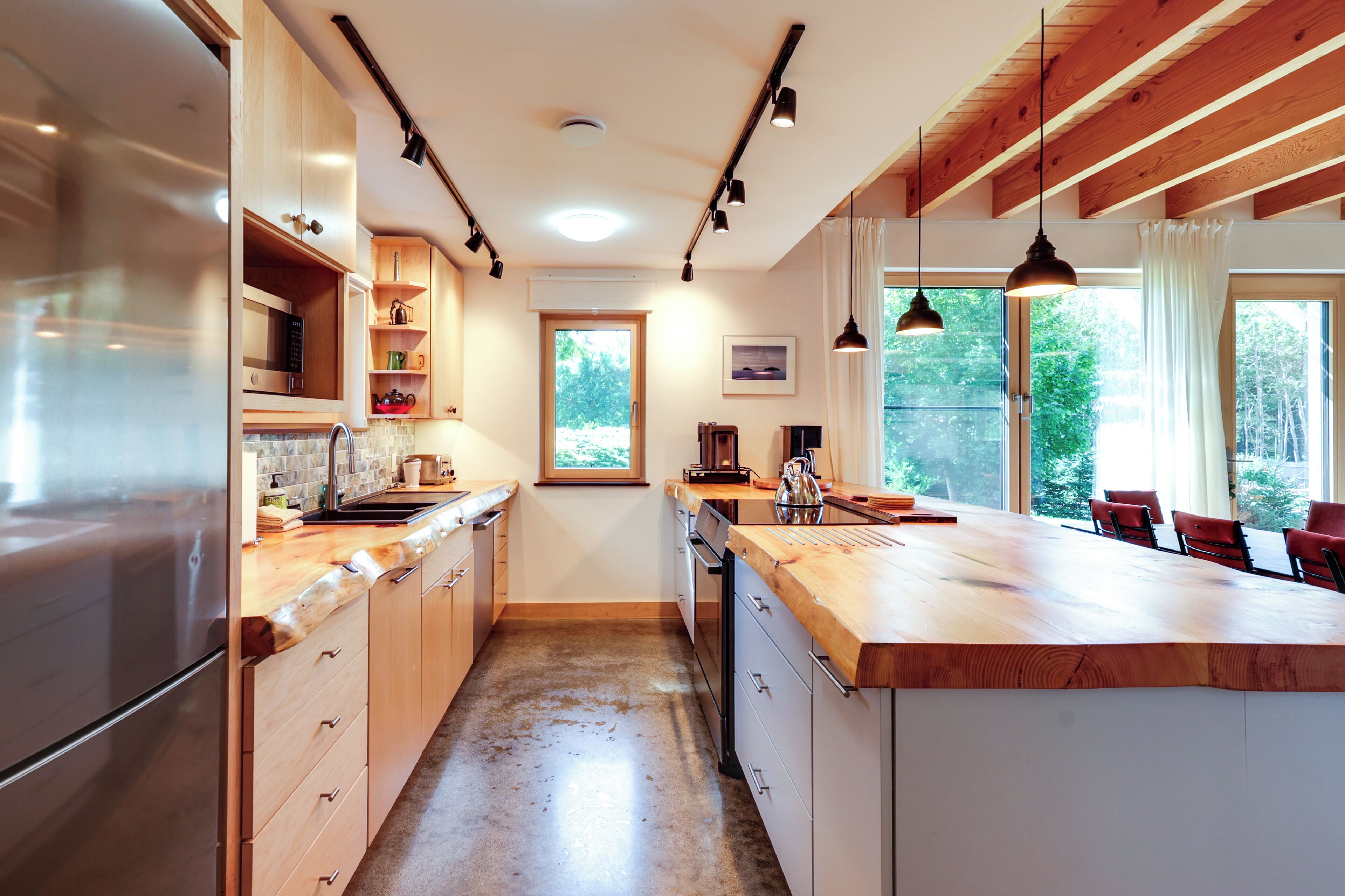 Una cocina moderna con armarios de madera, un refrigerador de acero inoxidable y una isla grande con encimera de madera.