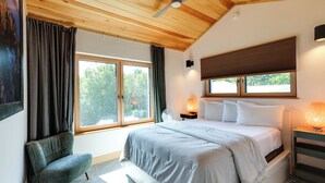 A bedroom with a large bed, a chair, a nightstand with a lamp, and a window with curtains. - Acadia Home w/ Rooftop Deck - Close to Trails! (Mount Desert)
