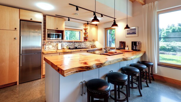 A modern kitchen with a large island, stainless steel appliances, and bar stools. - Acadia Home w/ Rooftop Deck - Close to Trails! (Mount Desert)