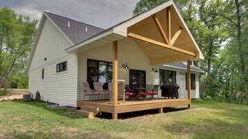 A single-story house with a covered porch, outdoor seating, and a grill.