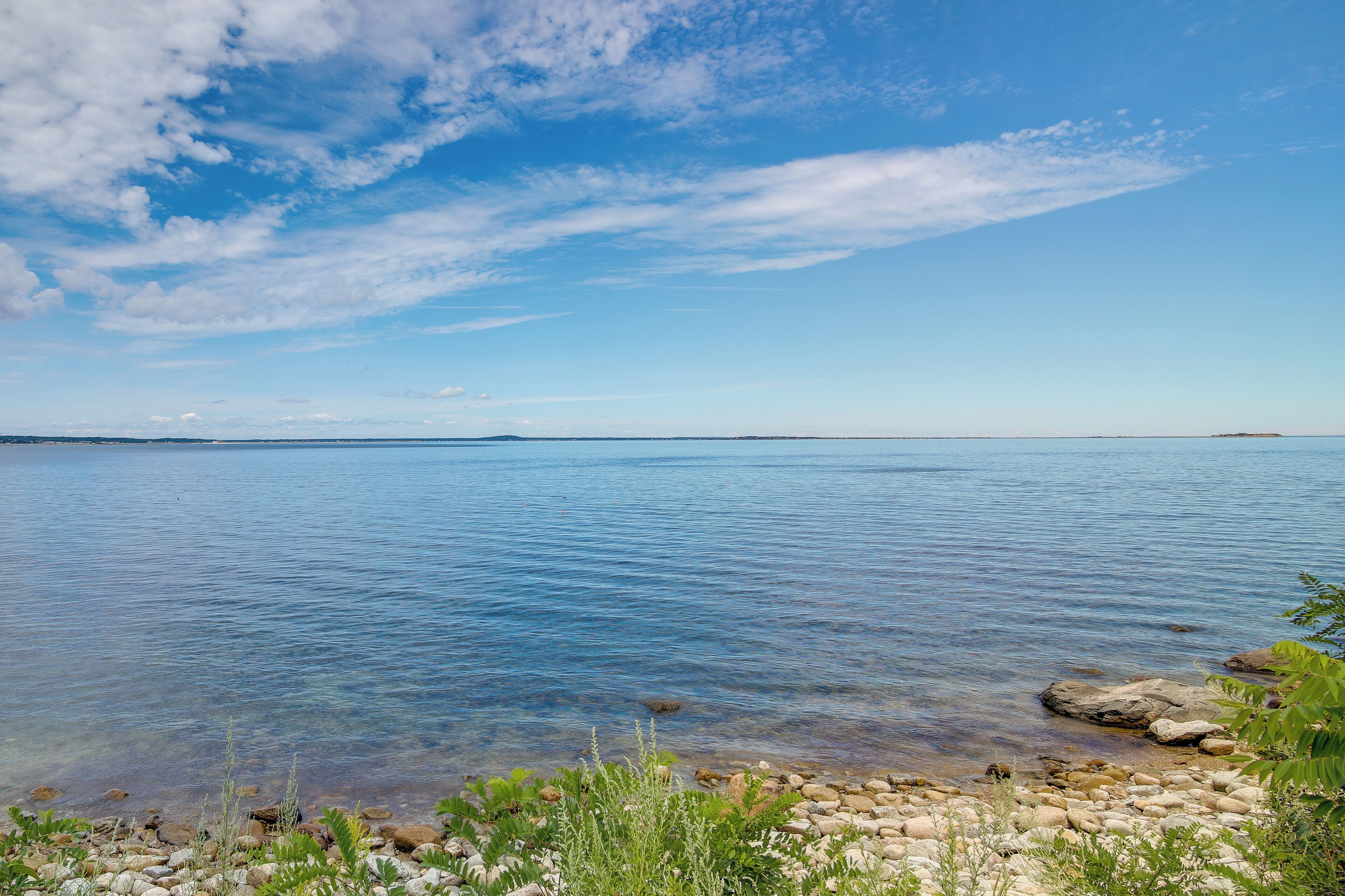 A calm lake with clear water, surrounded by rocks and vegetation.