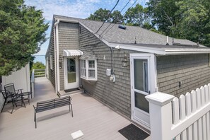 Une maison avec une terrasse, un banc, une porte et une fenêtre.