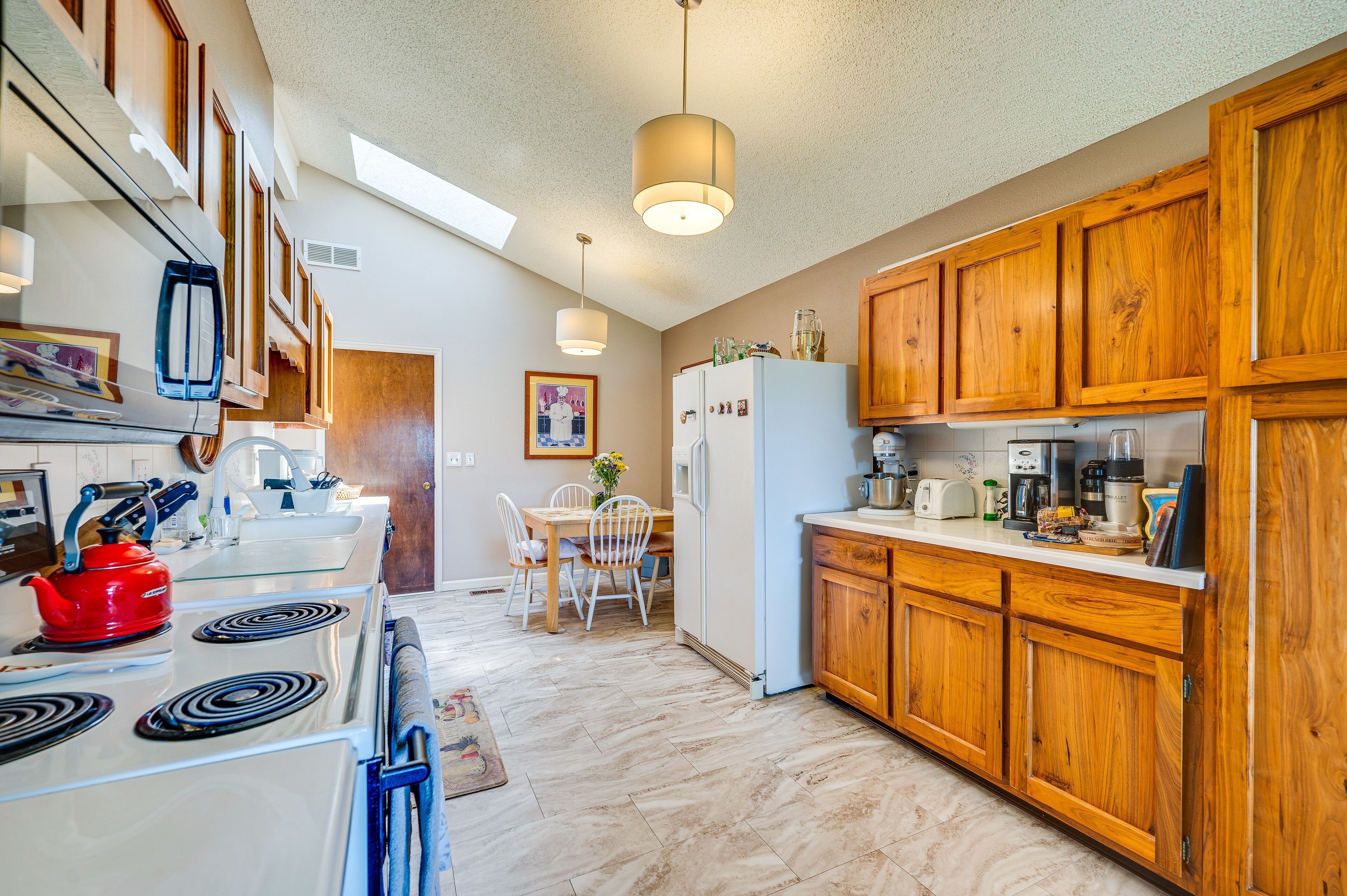 A kitchen with wooden cabinets, a white refrigerator, and a dining area with a table and chairs.