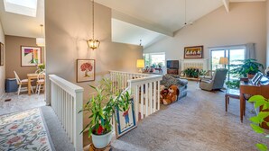 Un salon spacieux avec un plafond haut, une balustrade blanche, un piano et différents types de sièges.