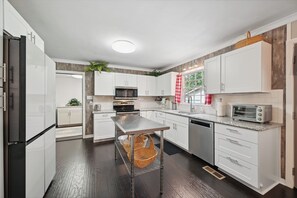 A modern kitchen with white cabinets, stainless steel appliances, and a central island. - Greensboro Golf Getaway - 9 Mi to Downtown! (Greensboro)