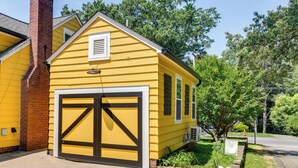 A yellow single-story house with a large garage door and a brick chimney. - 3 Mi to Dtwn Winston-salem: Studio on Miller Park! (Winston-Salem)