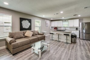 A modern kitchen with white cabinets, a stainless steel refrigerator, and a bar area.
