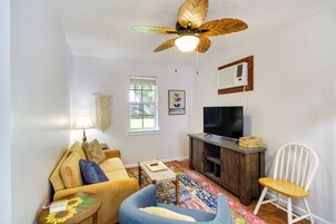 Una sala de estar con sofá, una mesa de centro, televisor, ventilador de techo, ventana y aire acondicionado instalado en la pared.
