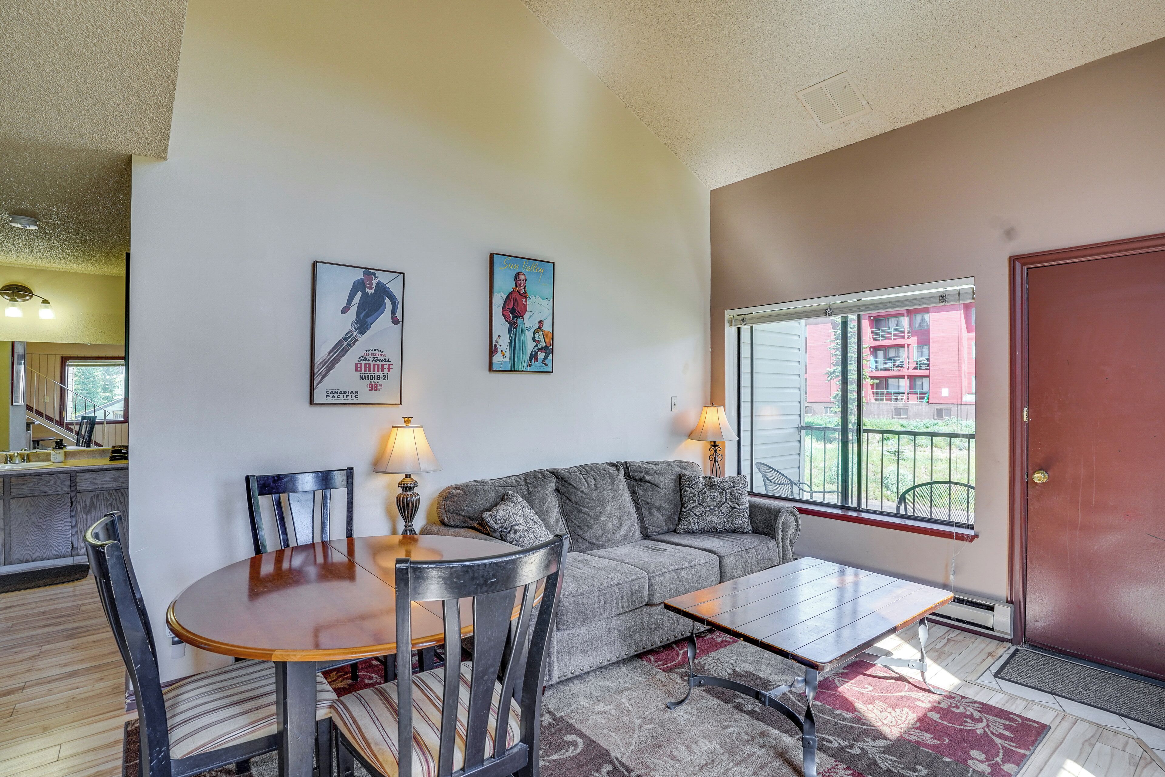 Un salon comprenant un canapé, des fauteuils, une table à manger et une fenêtre donnant sur des immeubles.