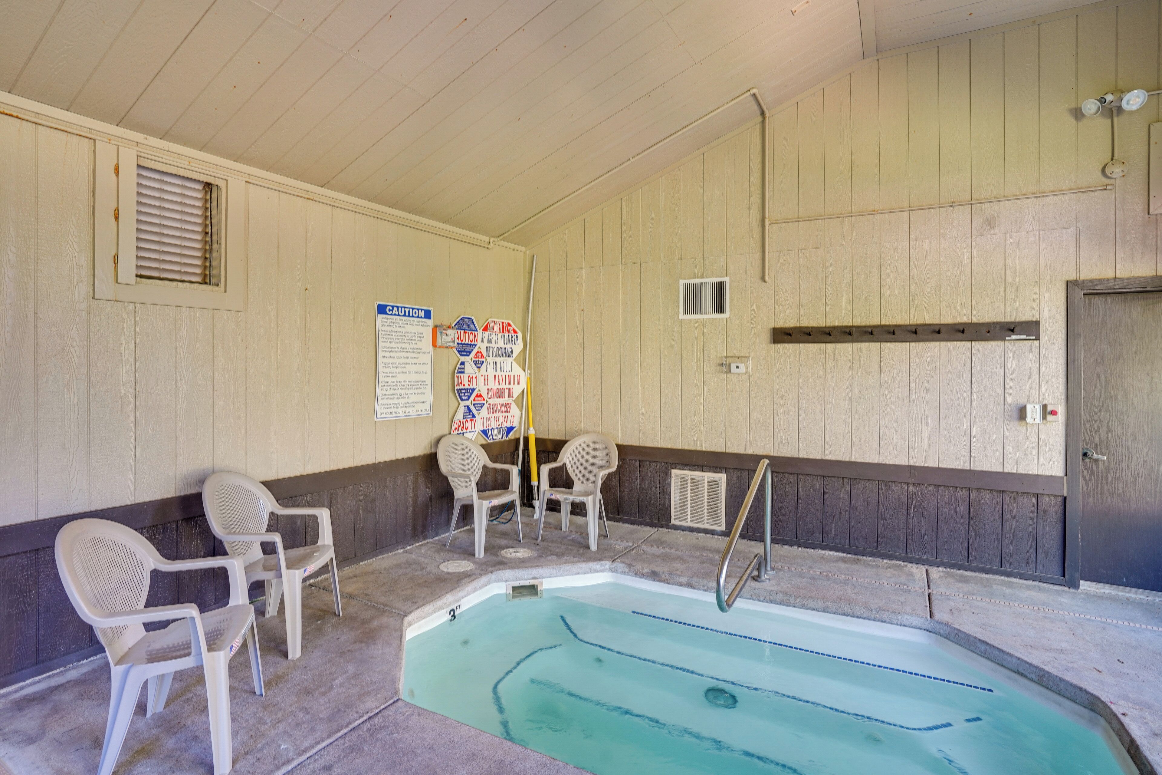 A pool area with a diving board, lounge chairs, and a sign with safety instructions.