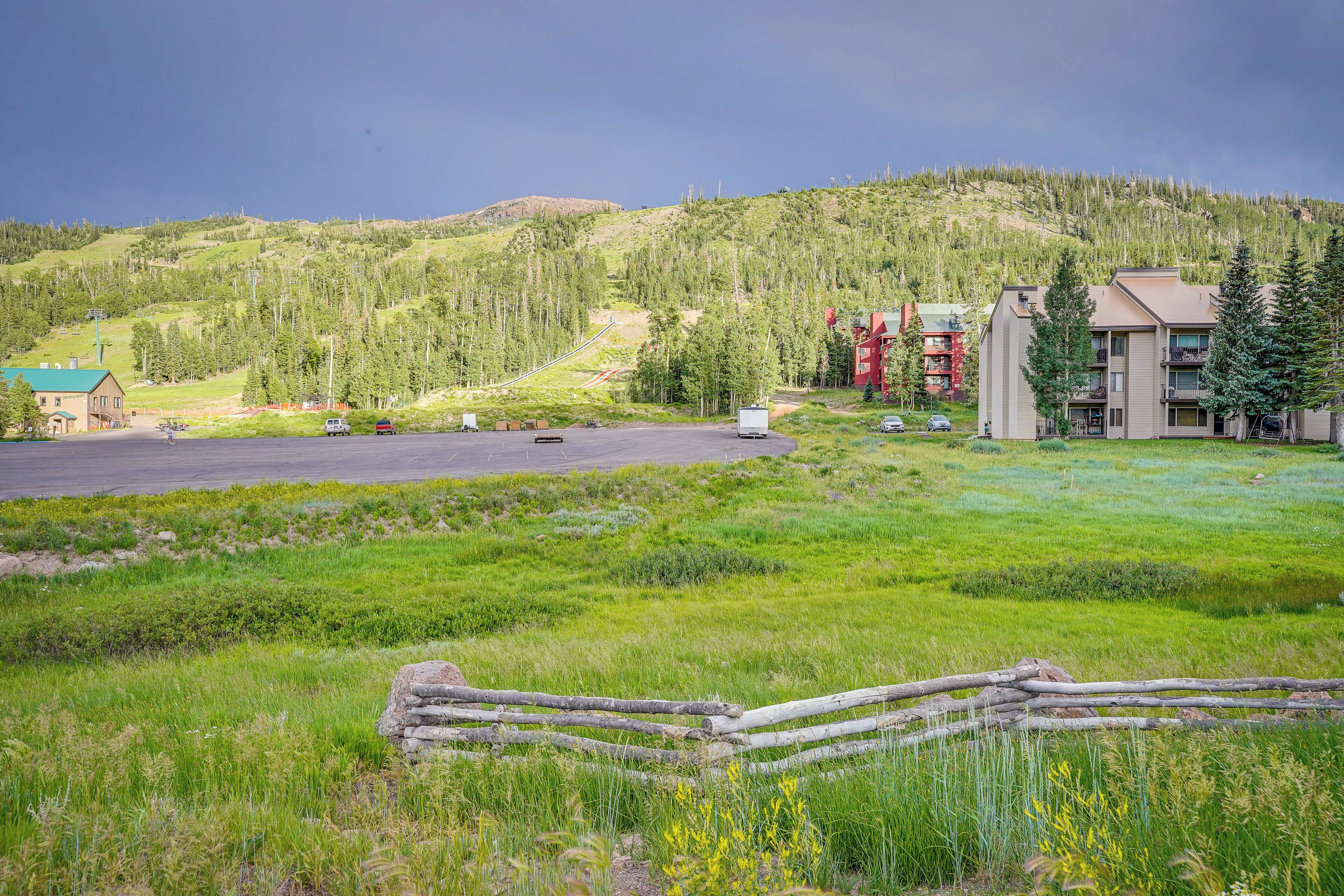 A hotel with a parking lot, a grassy area, and a mountainous backdrop.