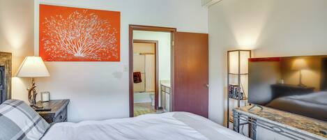 Ein Hotelzimmer mit einem Bett, einem Nachttisch mit Lampe, einem großen Spiegel und einem Fernseher.