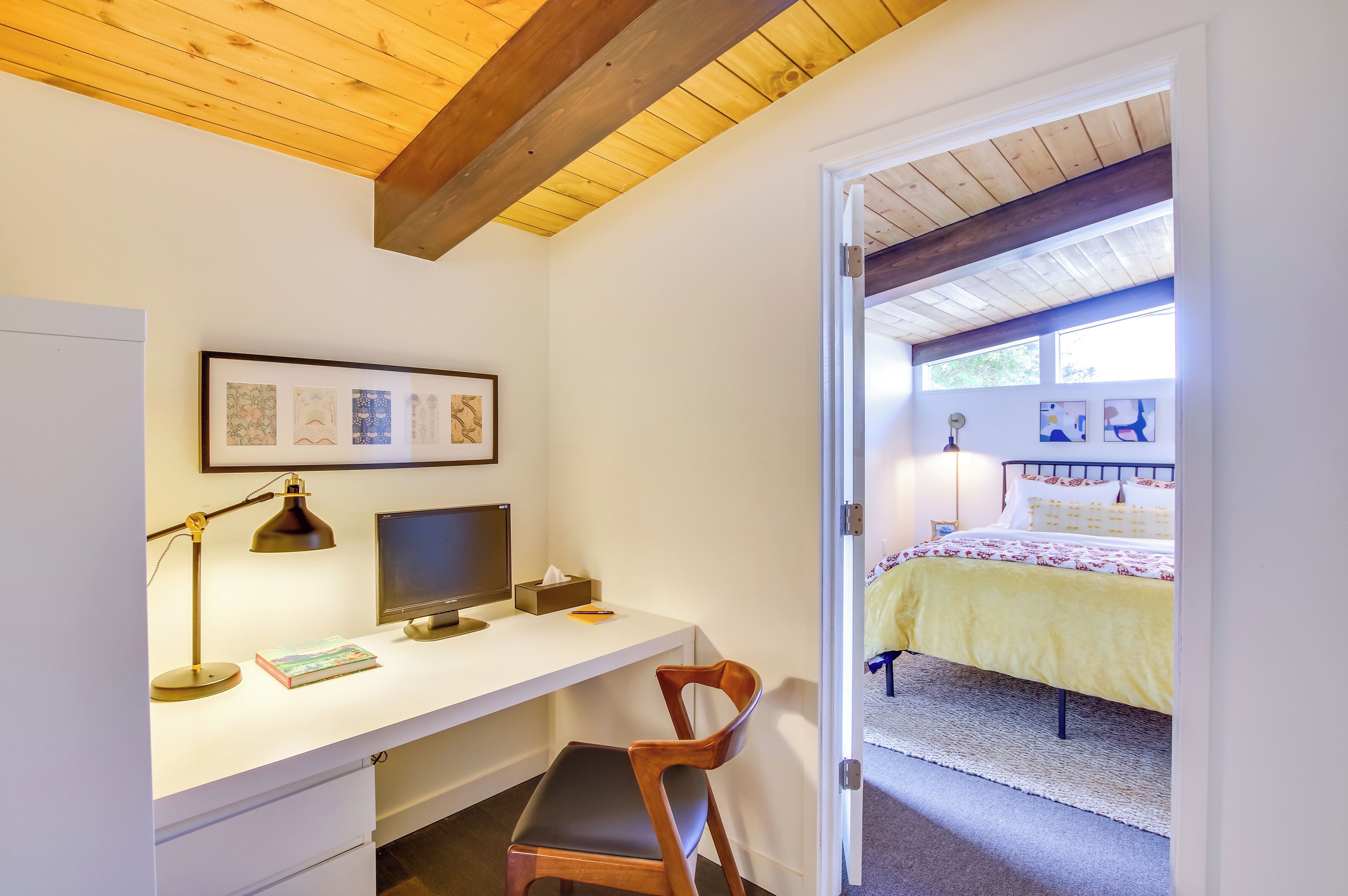 A bedroom with a bed, a desk with a computer, and a chair.