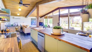 A modern kitchen with wooden countertops, a built-in dishwasher, and a large window providing natural light. - Whidbey Island Oasis: Walk to Beach, Hot Tub, View (Greenbank)