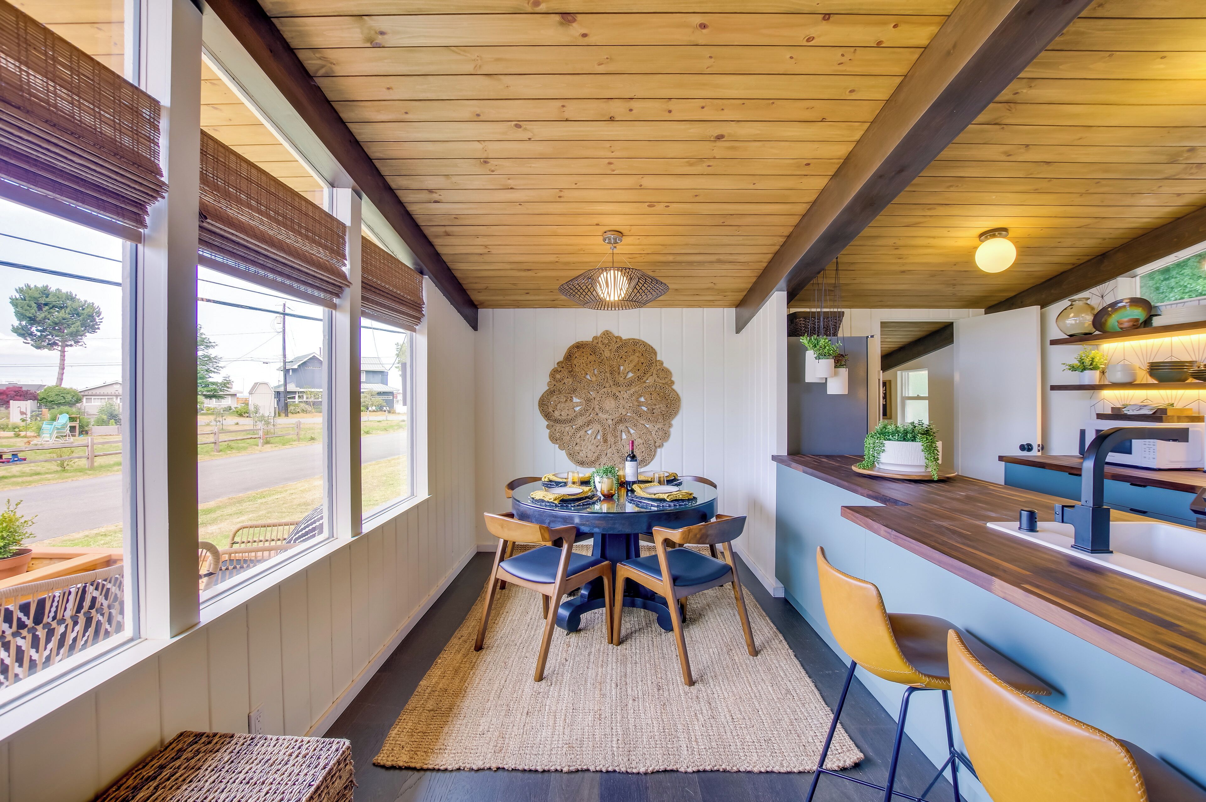 A dining area with a round table, chairs, and a view of the street outside.