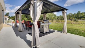 An outdoor patio with a covered grill area, a dining table with chairs, and a staircase leading to a house. - Lake Wales Vacation Rental Near Lake Kissimmee! (Lake Wales)