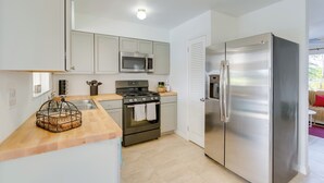 A modern kitchen with stainless steel appliances, a wooden countertop, and a built-in oven. - Riverfront Florida Retreat w/ Pool, Patio & Grill! (Port Charlotte)