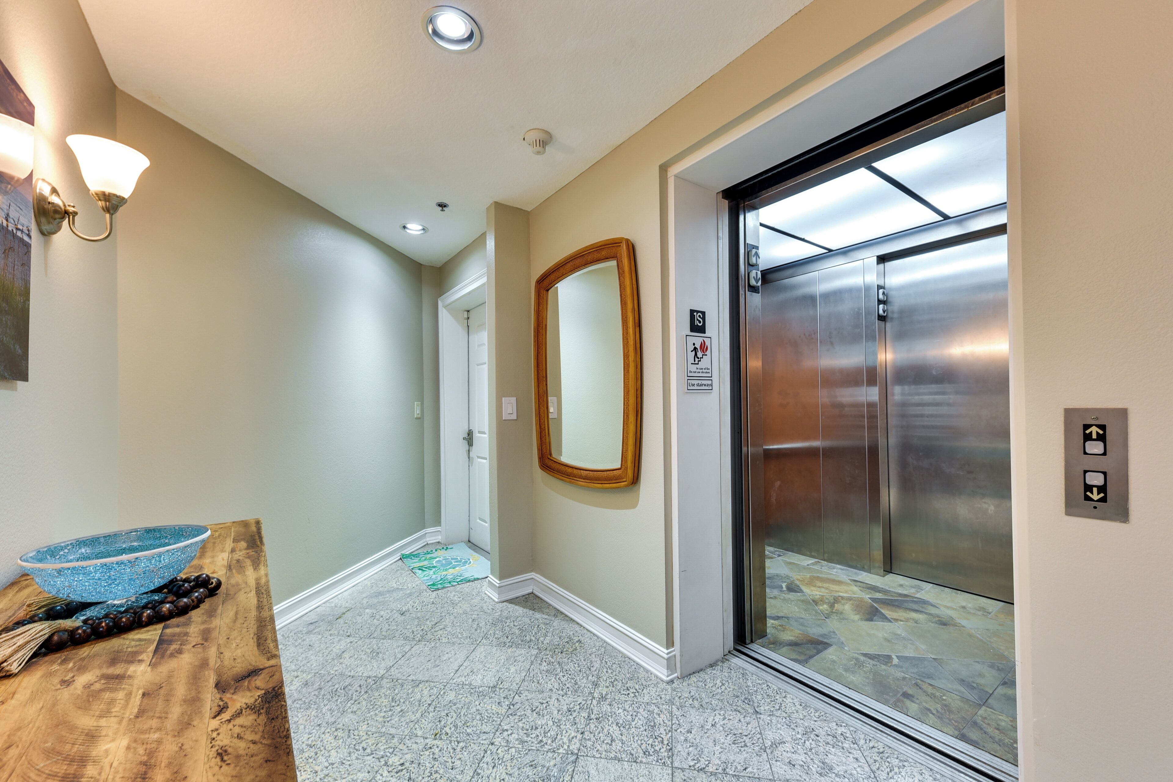 A hallway with a wooden table, a blue bowl, and a mirror on the wall.