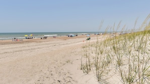 A sandy beach with people and beach umbrellas. - Pet-friendly Fernandina Beach Condo: Walk to Beach (Fernandina Beach)