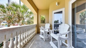 A balcony with white Adirondack chairs, a stone balustrade, and a view of palm trees. - Pet-friendly Fernandina Beach Condo: Walk to Beach (Fernandina Beach)