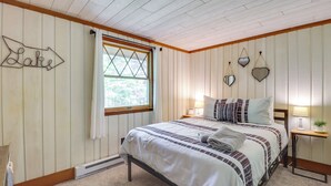 Une chambre à coucher comprenant un lit, une table de chevet, une fenêtre avec des rideaux, un panneau décoratif fixé au mur et un mur orné de miroirs.