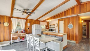 Une cabane en bois comprenant un coin repas, une cuisine et un espace salon confortable.
