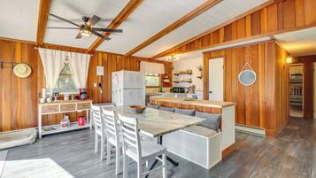 A wooden cabin with a dining area, kitchen, and a cozy seating area.
