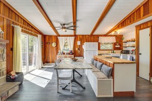 Uma cozinha acolhedora em estilo cabana, com paredes de madeira, uma mesa de jantar com cadeiras, um banco embutido e uma geladeira.