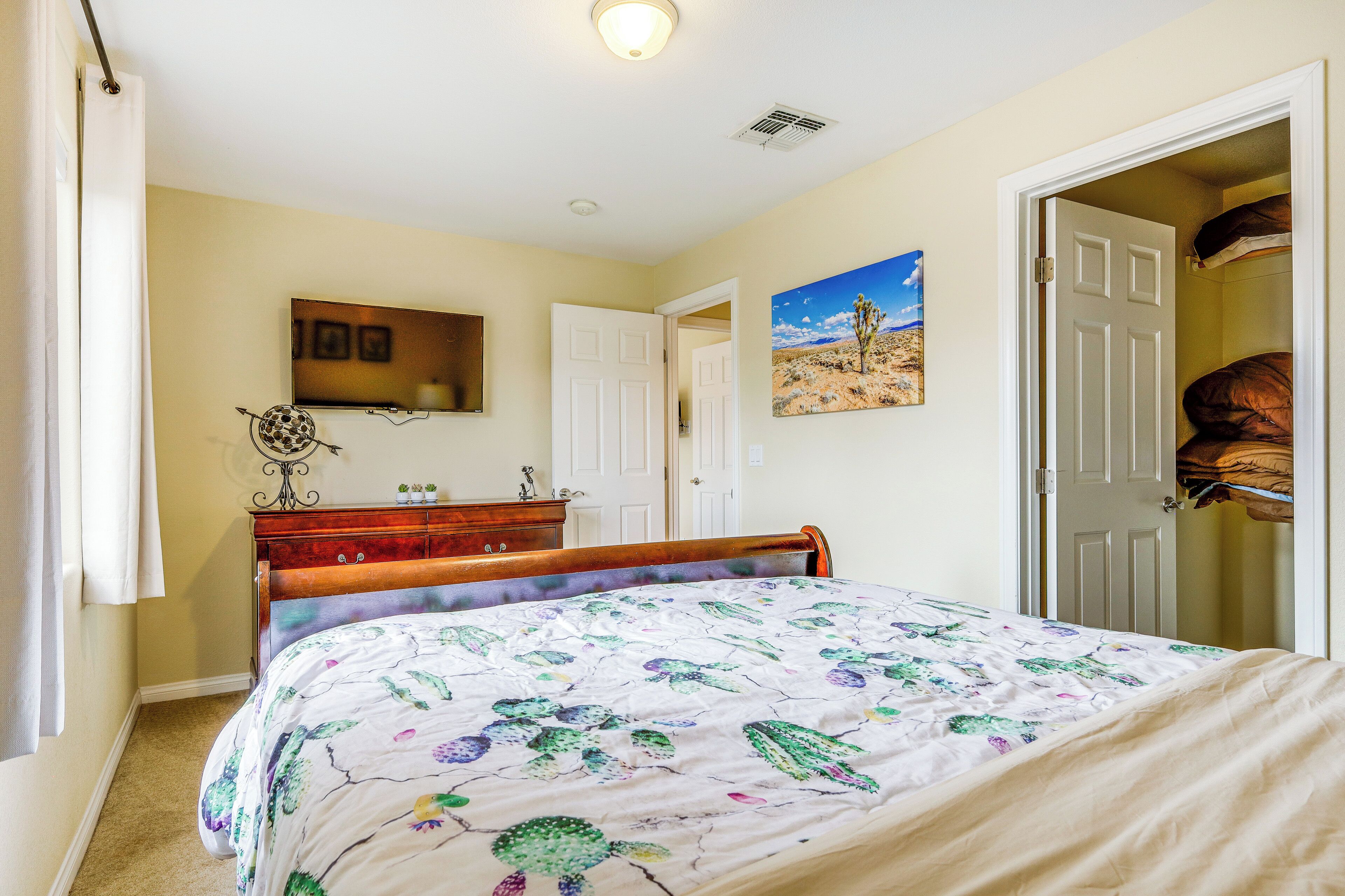 Une chambre à coucher avec un lit, une commode, un tableau et un placard.
