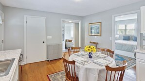 En spiseplads med et rundt bord dækket til fire personer, en radiator og udsigt til et soveværelse.