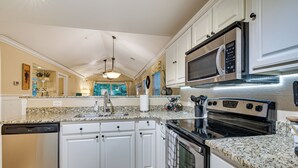 A kitchen with white cabinets, a stainless steel dishwasher, a microwave, and an oven. - Highend Pawleys Island Condo w/ Porch & Pools! (Pawleys Island)