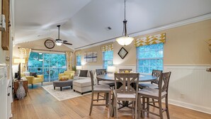 A spacious living room with a dining area, large windows, and a ceiling fan. - Highend Pawleys Island Condo w/ Porch & Pools! (Pawleys Island)