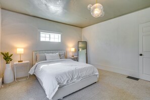 Quarto com cama, mesas de cabeceira, janela e porta.