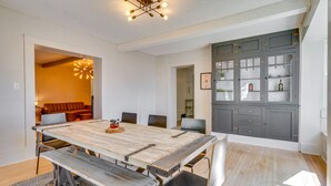 A dining area with a large wooden table, benches, and chairs. There is a kitchen with grey cabinets and a chandelier above the table. - Pet-friendly Pueblo Vacation Rental w/ Patio! (Pueblo)