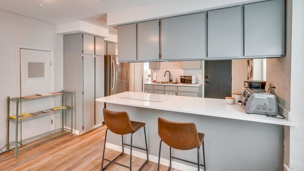 A modern kitchen with a white island, stainless steel appliances, and two bar stools. - Pet-friendly Pueblo Vacation Rental w/ Patio! (Pueblo)